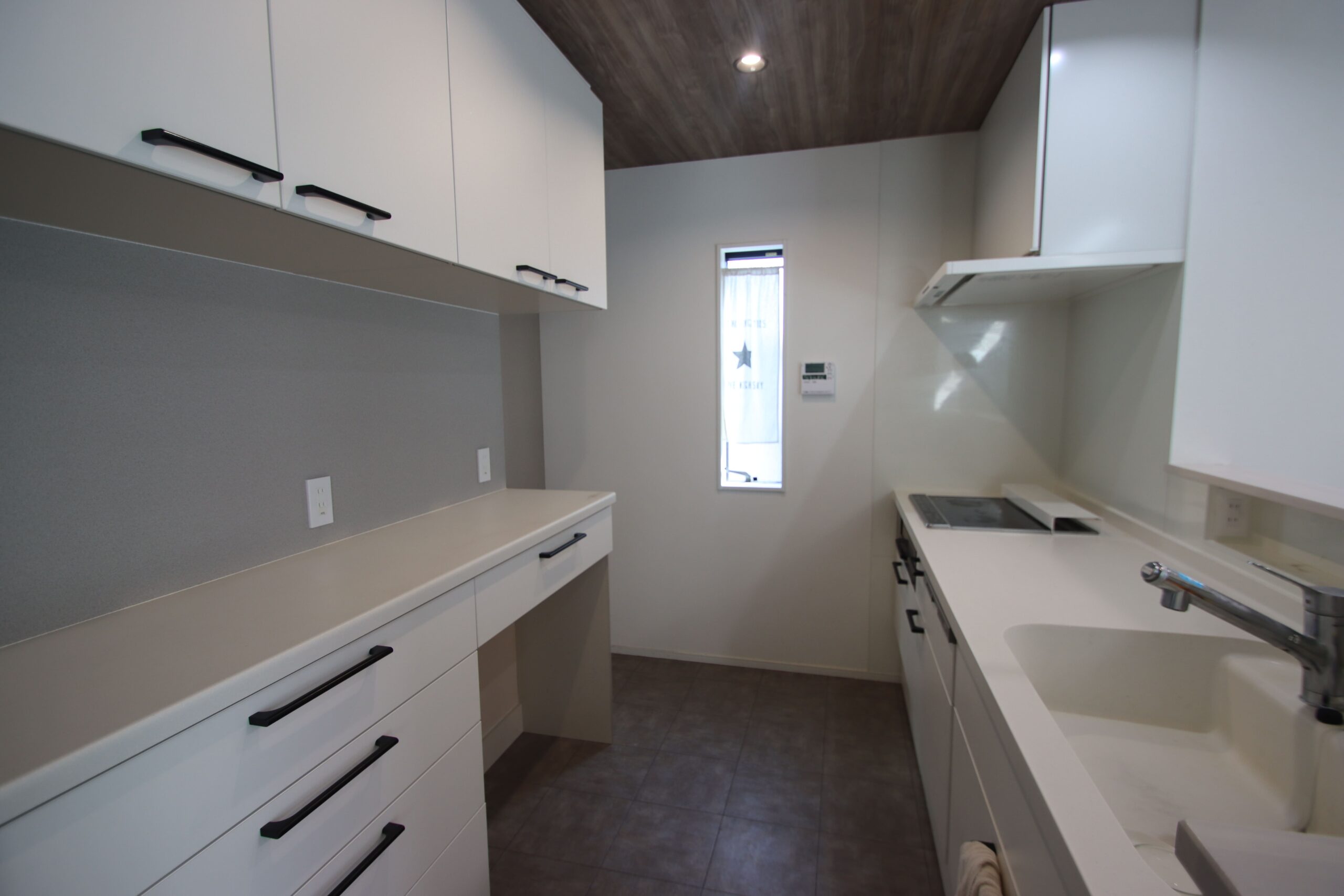 白基調の明るいカップボード付きシステムキッチン。収納もたっぷり。